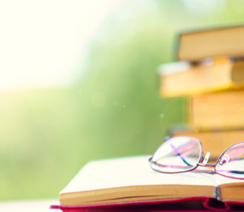 A pile of books with reading glasses on top