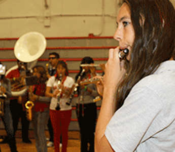 Student playing an instrument in the gym