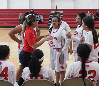 Coach talking with girls basketball team during game