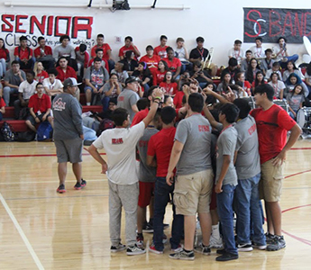 Students huddling up on the basketball court during spirit week